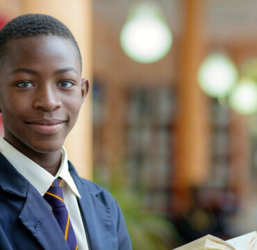boy-wearing-school-uniform-is-smiling-holding-book