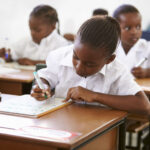 Schoolgirl writing at her desk in elementary school lesson